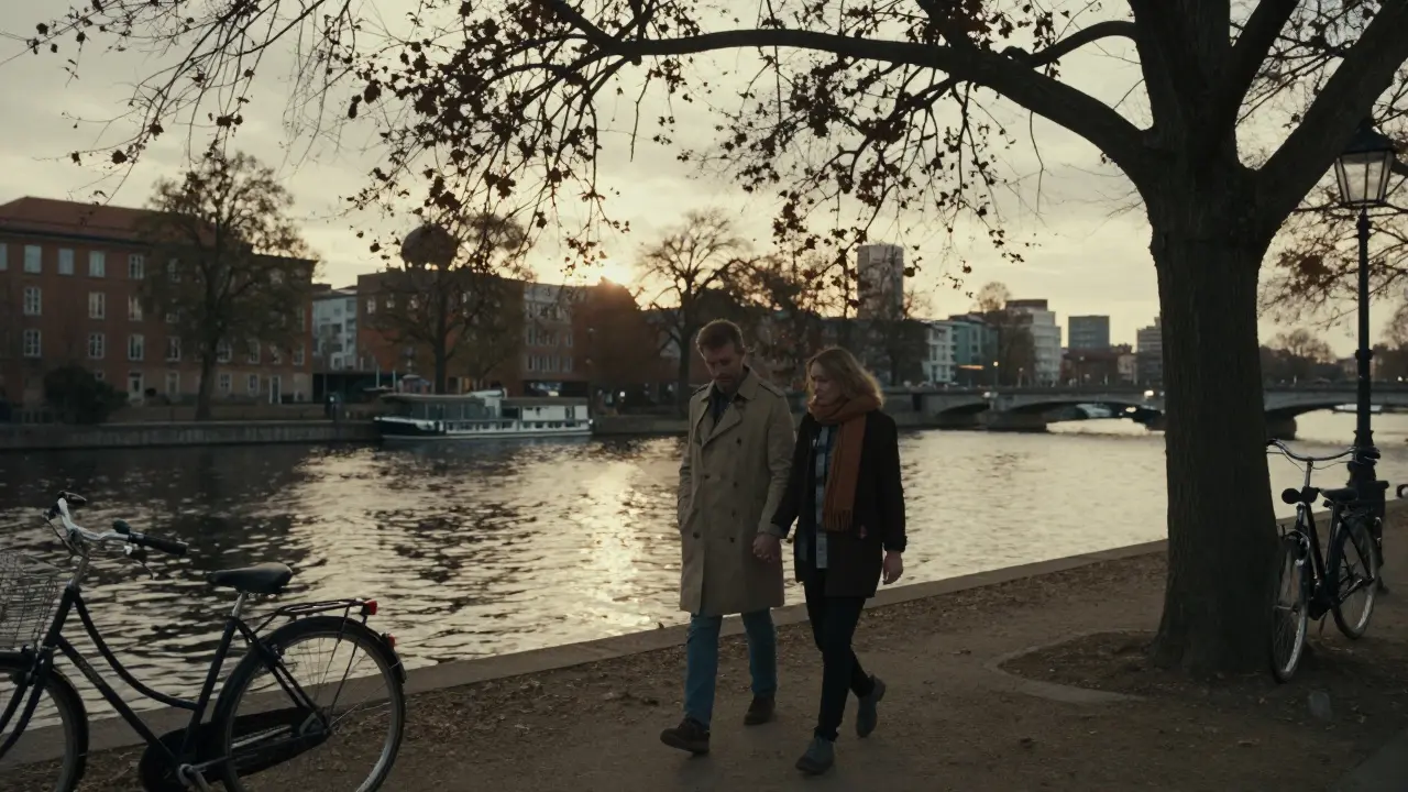A couple walking hand in hand along the Spree River at sunset, surrounded by trees and soft city lights.