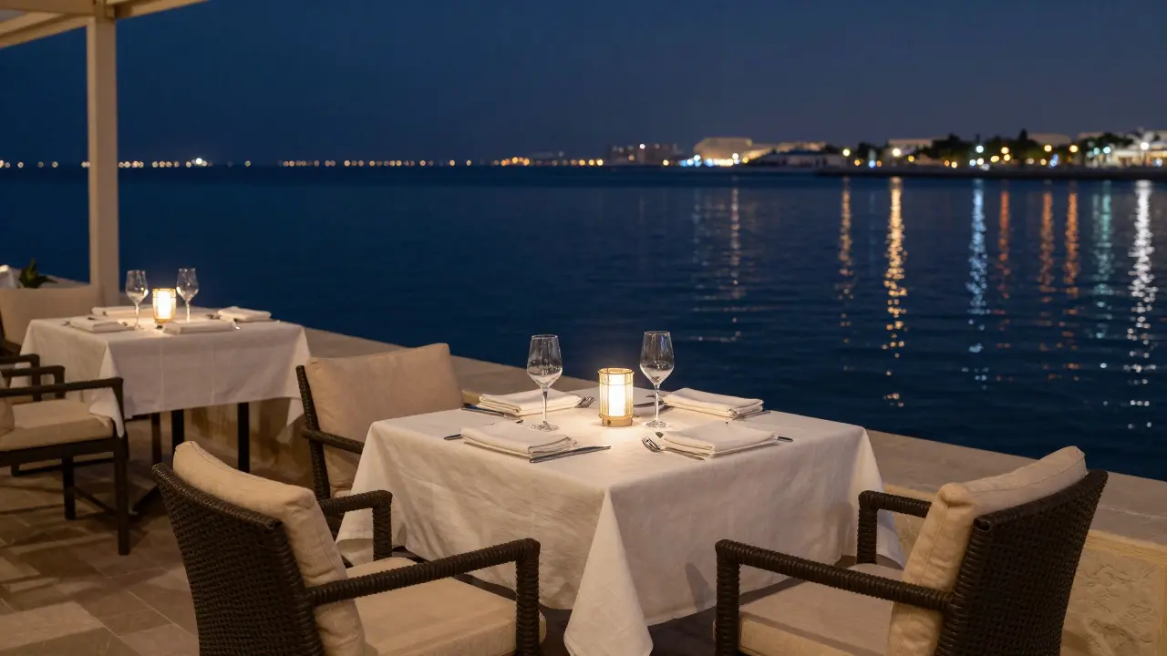 Waterfront dinner table overlooking calm sea at night.